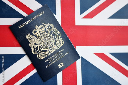 Blue British passport on national flag background close up. Tourism and citizenship concept