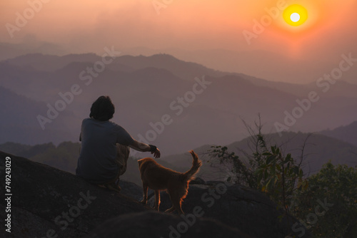 landscape and travel concept with solo freelancer man relax and play with dog at top of mountain and sunset with layer of mountain