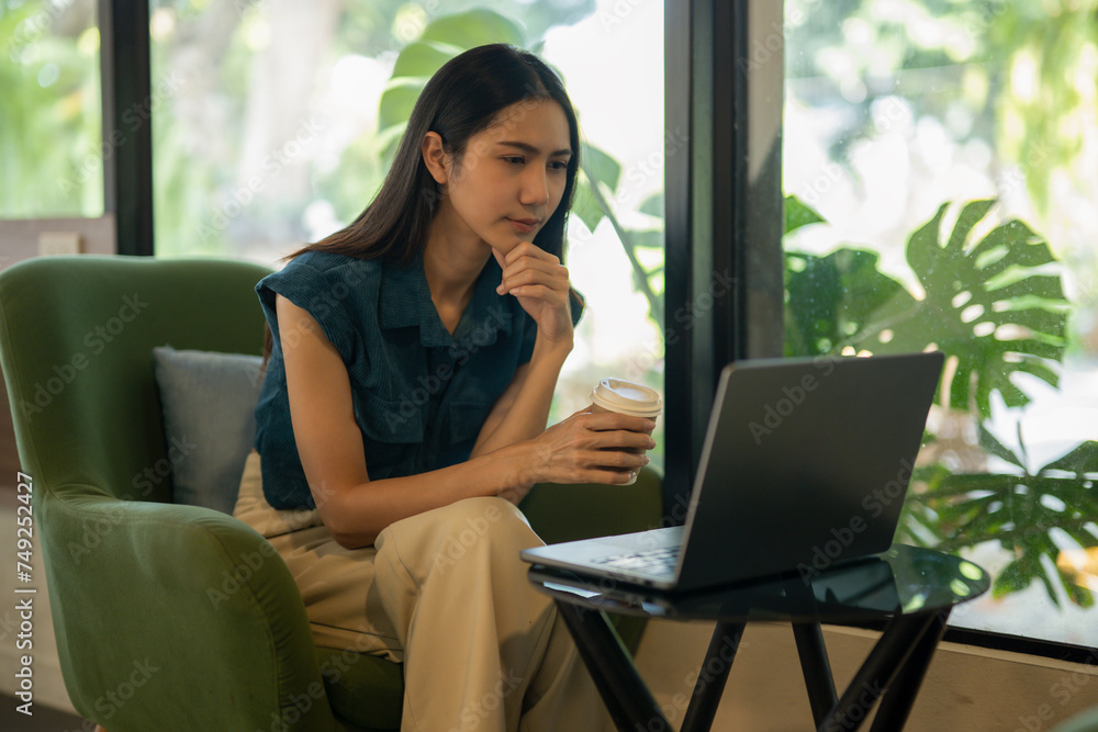Contemplative young woman looking out window in coffee shop with laptop and coffee cup Contemplative young woman looking out window in coffee shop with laptop and coffee cup