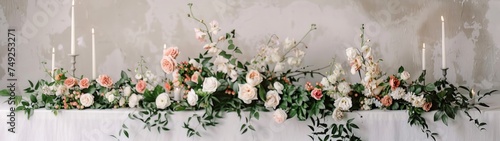 Visualize a sweetheart table set apart from the rest, featuring a lavish floral arrangement that spills over the edges of the table, with roses, peonies, and cascading greenery.