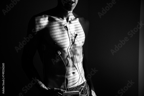 Fototapeta Naklejka Na Ścianę i Meble -  Capturing the heart's rhythm: EKG patterns on a young man, bathed in the radiance of natural daylight. Black and white photo. Edit psace