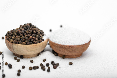 Dwie drewniane miseczki z solą kuchenna i czarnym pieprzem izolowane na jasnym tle