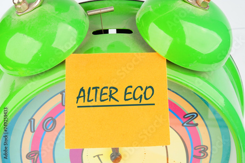 Text Alter ego is translated from Latin as the second self. a real or invented alternative personality of a person. Written on the orange sticker on the alarm clock photo