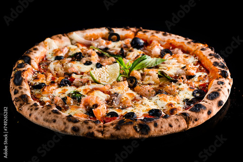 Italian pizza with salmon, onion, olives, cheese, basil, tomato sauce, lime and spices on black.