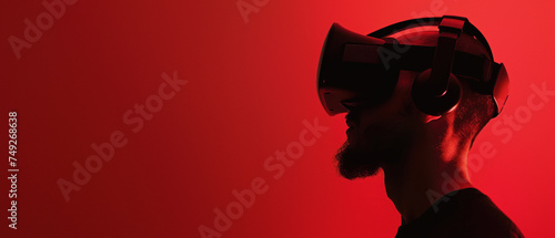 Side profile of an individual deeply engaged in a virtual reality session on a scarlet background photo