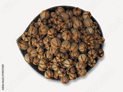 Pride of India dry seeds (Lagerstroemia speciosa) in a bowl isolated on white background, other common names :  Queen’s Flower, Queen’s Crape Myrtle. 