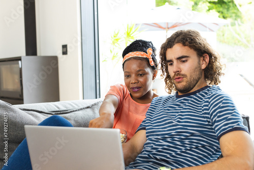 Diverse couple young African American woman and Caucasian man sit together with a laptop
