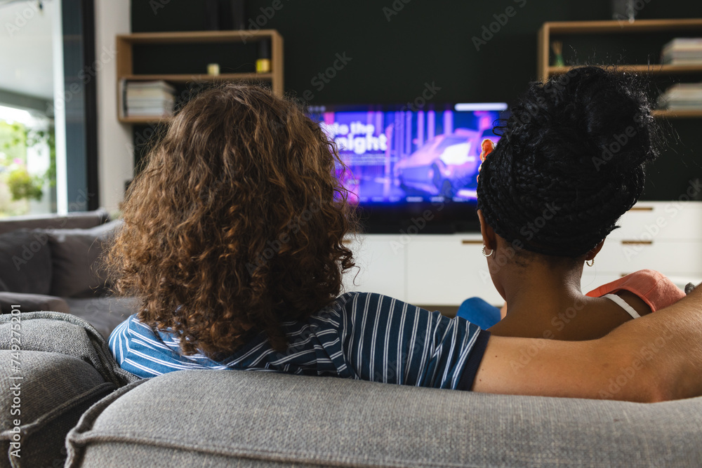 Diverse couple young Caucasian man and African American woman relax on a sofa, watching TV together Diverse couple young Caucasian man and African American woman relax on a sofa, watching TV together