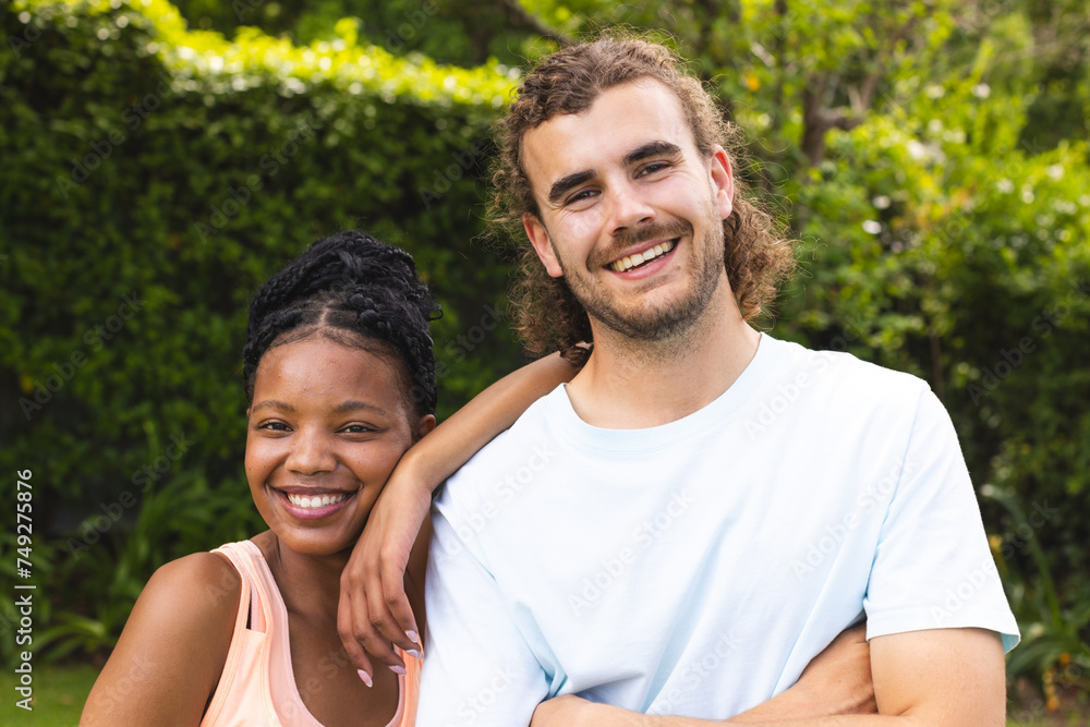 Diverse couple, a young African American woman and young Caucasian man, are smiling outdoors