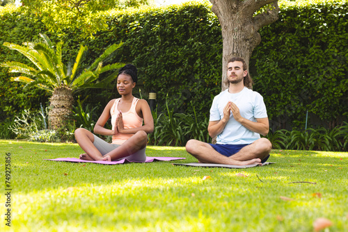 A diverse couple, a young African American woman and a young Caucasian man, are meditating in a sere