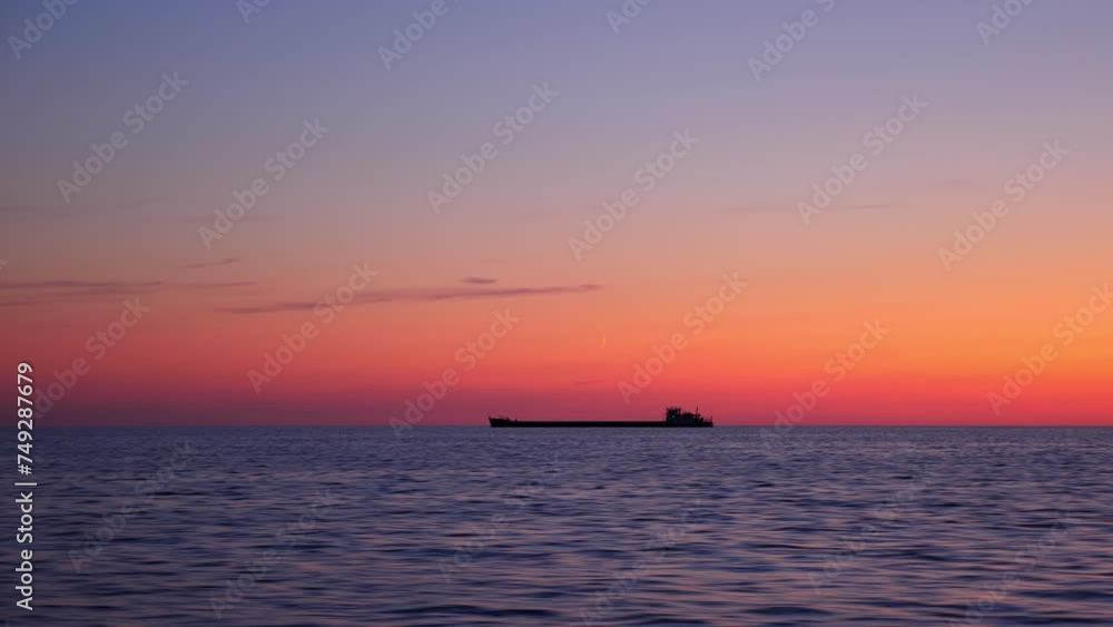 Silhouette of cargo ship is visible on horizon, captured from fast-moving boat. Surface of lake rushes by, tranquil yet dynamic, as vessel sails swiftly through water. Silhouette of cargo ship is visible on horizon, captured from fast-moving boat. Surface of lake rushes by, tranquil yet dynamic, as vessel sails swiftly through water.