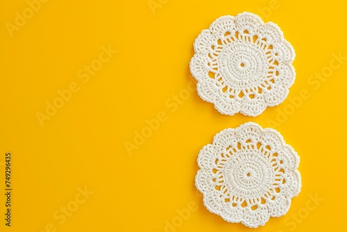 White crochet doilies on a yellow background with copy space.