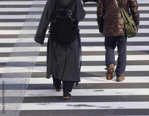 冬の朝の街の交差点の横断歩道を渡る人々の姿
