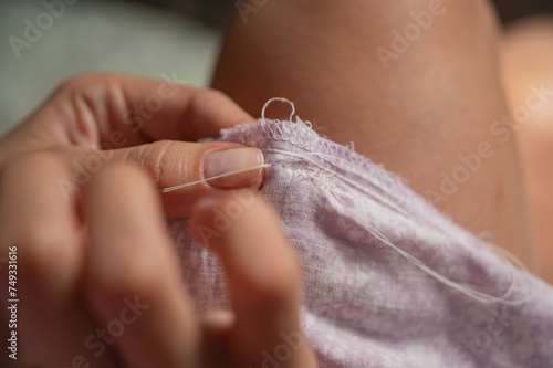 seamstress hands with a needle, repairing clothes using thread and needle. Clothing repair