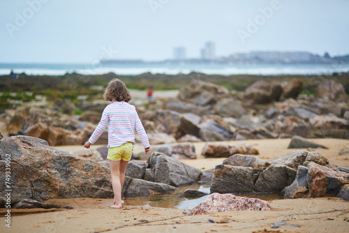 Adorable preschooler girl playing on the beach at Atlantic coast of Brittany, France photo