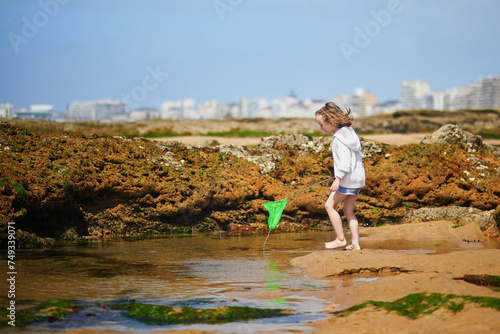 Adorable preschooler girl playing with scoop net on the beach at Atlantic coast of Brittany, France