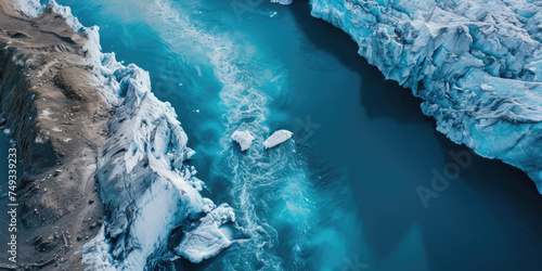 Aerial view of a melting glacier edge with floating icebergs in icy blue waters.
