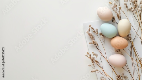 Easter pastel colored eggs with spring flowers on white background, copy space, top view
