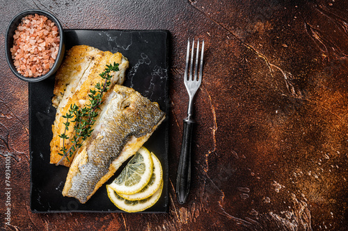 Roast sea bass fillet with lemon and thyme, seabass fish. Dark background. Top view. Copy space photo