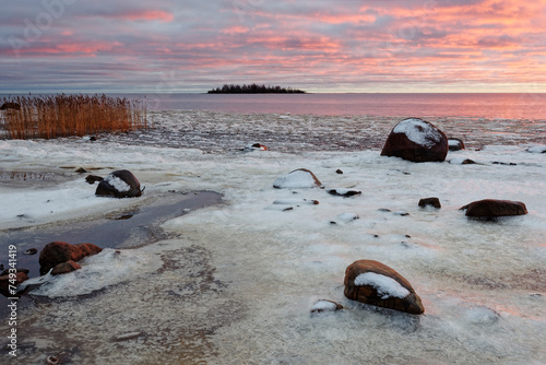 Colorful sunset by the wintry sea with some ice on the beach, Bothnian Bay, Baltic Sea, Finland