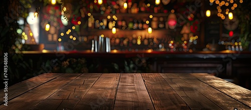 An empty wooden table is set in front of a bar at a restaurant. The background features bokeh lights, creating a warm and inviting atmosphere. © 2rogan