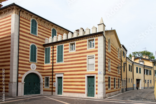 Low angle view of some of the traditional buildings in the inner city of Bardolino, Italy along Lake Garda; buildings with colorful yellow and orange stripes and green shutters and doors