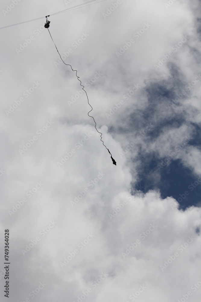 Silhouette of a person hanging on a cord during bungee jump in a open sky Silhouette of a person hanging on a cord during bungee jump in a open sky