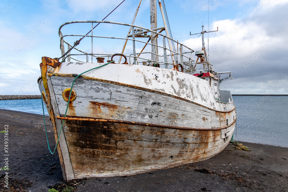 Front bow view of a beached, shipwrecked, abandoned fishing boat on the black sand beach near Utnesvegur on the western side of Iceland from the port of Sandgerdi