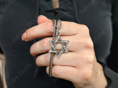 Young woman's hand holding a David Star ("Magen David") key chain. The State of Israel, Judaism, Zionism concept image. Conversion to Judaism. Passover. 