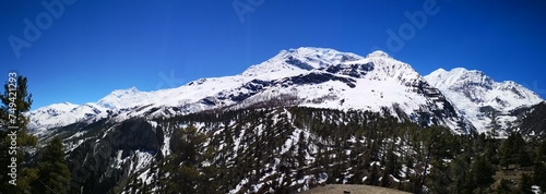 A majestic snow-capped mountain, glistening white, framed by a clear blue sky, showcasing nature's breathtaking beauty.