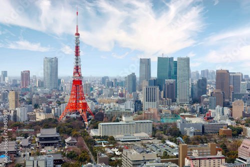 Beautiful city skyline of Downtown Tokyo, with the famous Tokyo Tower standing tall among modern skyscrapers under blue sunny sky & Zoujou-ji Buddhist Temple near the base of the eye-catching landmark