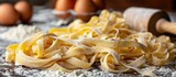 Freshly made tagliatelle pasta piled on a wooden table with a light dusting of flour.