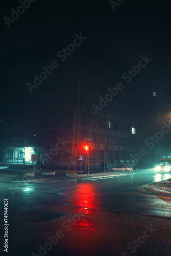Street lights and fogger in fog at intersection with driving cars, vertical photo