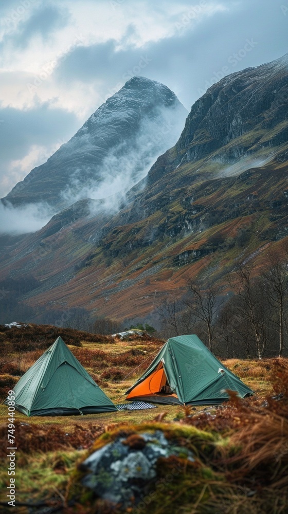A couple of tents set up on top of a grass-covered field in the Highlands, showcasing a camping site.