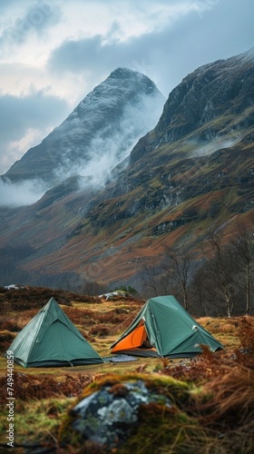 A couple of tents set up on top of a grass-covered field in the Highlands, showcasing a camping site.