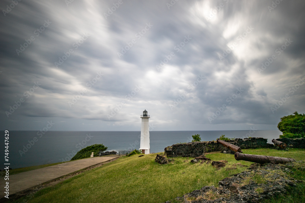 Le Phare du Vieux-Fort, white lighthouse on a cliff. Dramatic clouds overlooking the sea. Pure Caribbean on Guadeloupe, French Antilles, France - obrazy, fototapety, plakaty 