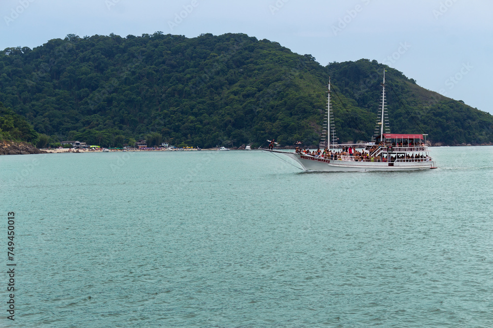 SANTOS, SP, BRAZIL - JANUARY 02, 2024: Schooner with tourists sailing in the estuary in front of Goes beach.