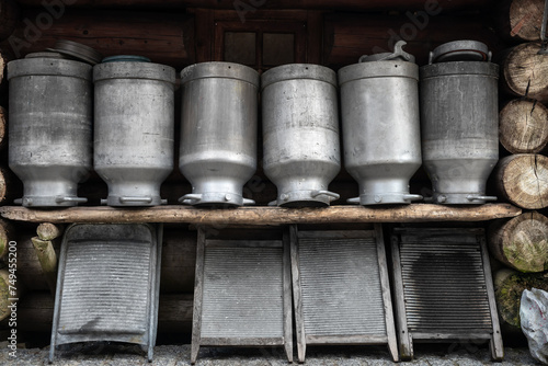 Metalowe artykuły gospodarskie ustawione na ławce przy wiejskiej drewnianej chacie © piotr