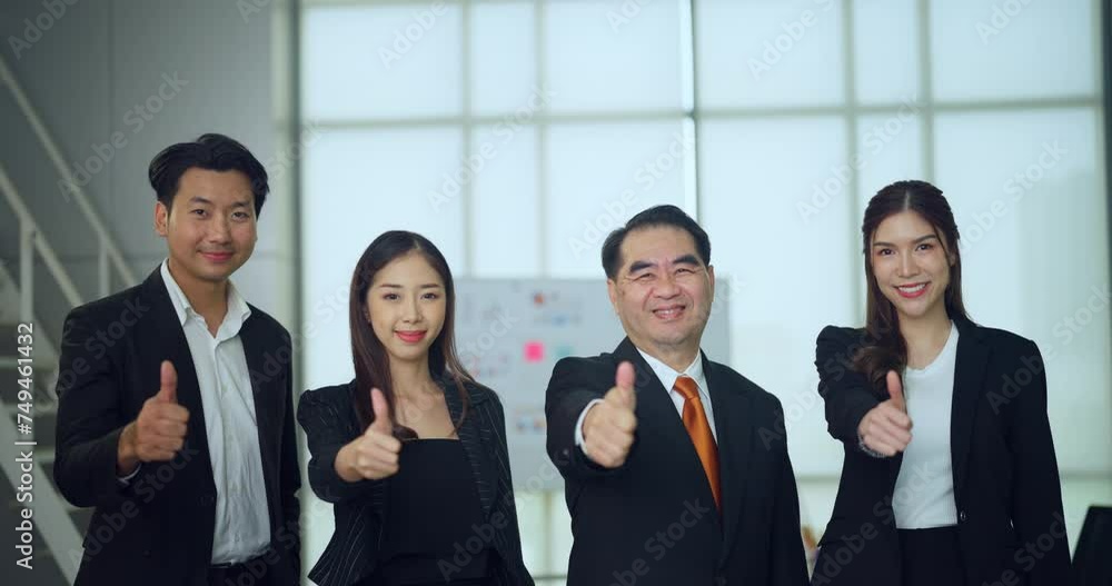 Four smiling business professionals in formal attire giving a thumbs-up gesture in a bright office environment, expressing approval or success. Four smiling business professionals in formal attire giving a thumbs-up gesture in a bright office environment, expressing approval or success.