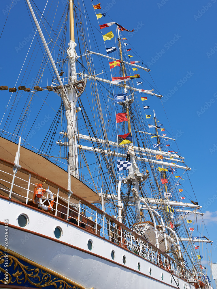 Fototapeta premium Ship, water and harbor at sea to coast guard with landscape, blue sky and nautical flags for emergency sailing. Vessel, dock and ocean with safety for maritime, danger and patrol in morning or nature
