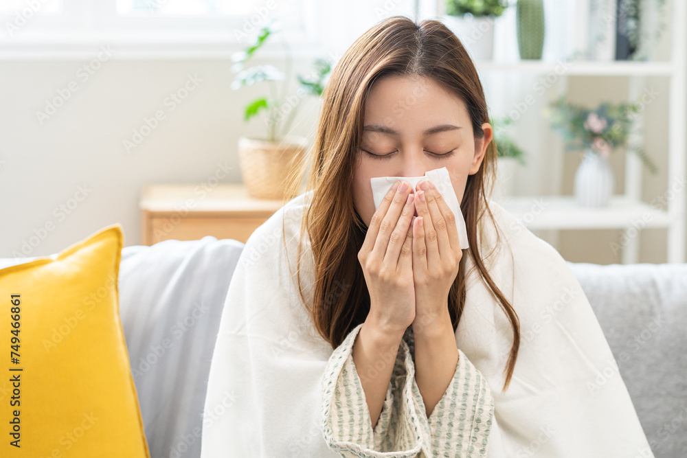 Sick, coronavirus or covid, tired asian young woman have a fever, flu and hand in use tissues paper sneezing nose, runny while sitting on sofa, couch at home. Health care with disease, pandemic virus Sick, coronavirus or covid, tired asian young woman have a fever, flu and hand in use tissues paper sneezing nose, runny while sitting on sofa, couch at home. Health care with disease, pandemic virus