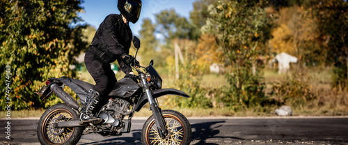 a motorcyclist wearing a helmet and motorcycle boots rides an enduro motorcycle in nature.