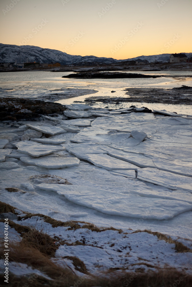 Frozen sea, with yellow hue of winter sun, Sommaroy near Tromso, northern Norway