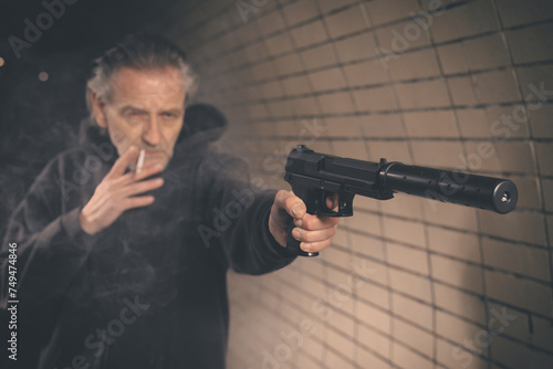 Old member of criminal  gang armed with handgun shooting in gun smoke