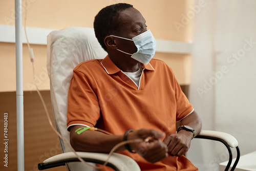 Foto Side view of Adult African American man wearing mask while getting IV drip treat