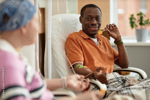 Photos Portrait of smiling African American man talking to another patient and holding