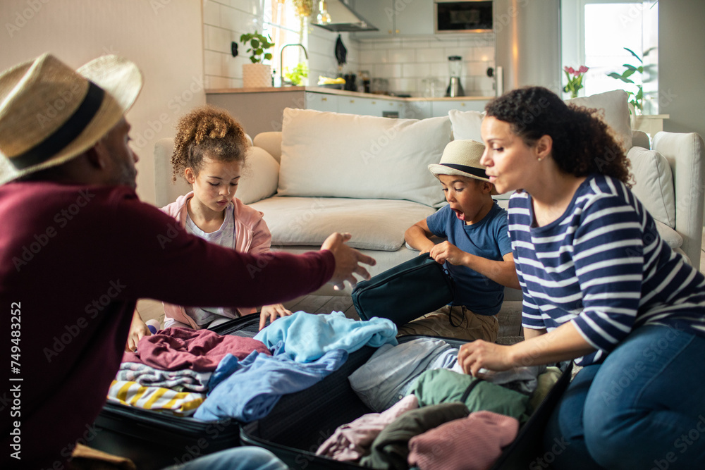 Family packing suitcase together for vacation in living room Family packing suitcase together for vacation in living room