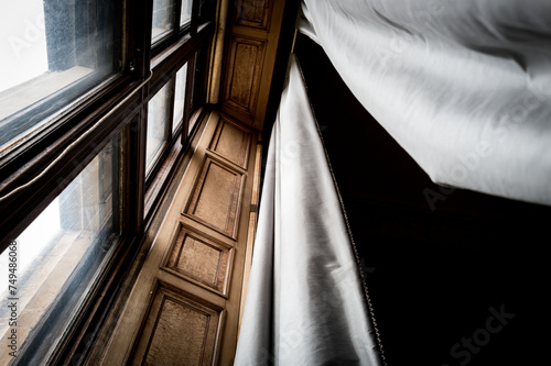 Vertical view of long fabric curtains and an equally large bay window since in a private home in the UK. The interior is of a Staley home in the UK. photo