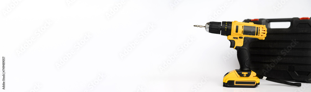 Banner, electric cordless yellow drill screwdriver and black carrying case on a white background. Concept of construction, repair, electrical equipment, modern tools. Copy space. Advertising space Banner, electric cordless yellow drill screwdriver and black carrying case on a white background. Concept of construction, repair, electrical equipment, modern tools. Copy space. Advertising space