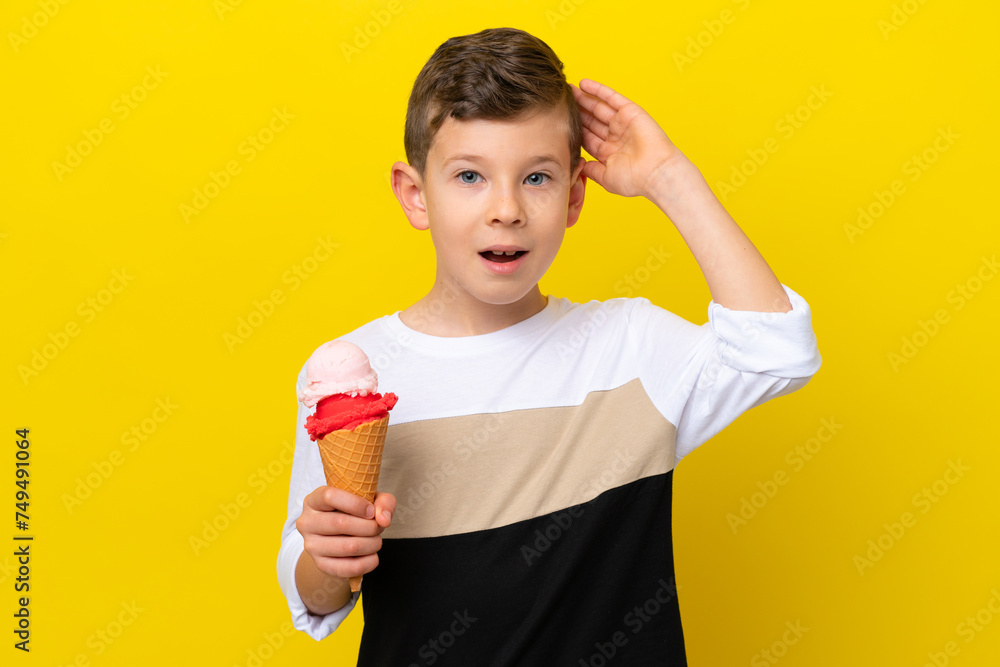 Little caucasian boy with a cornet ice cream isolated on yellow background with surprise expression Little caucasian boy with a cornet ice cream isolated on yellow background with surprise expression